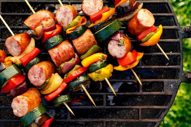 Grilled Skewers Of Meat, Sausages And Various Vegetables On A Gr