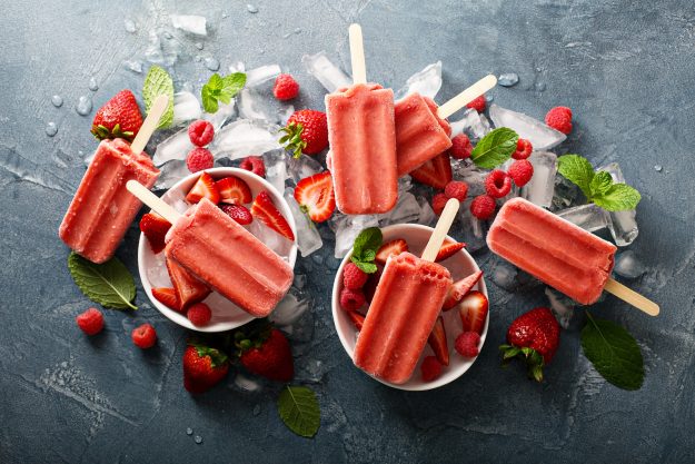 Strawberry and raspberry ice cream popsicles in white bowls